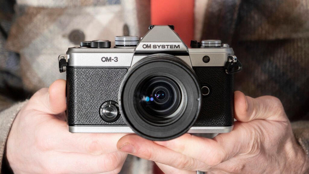 OM System OM-3 mirrorless camera in the hand, 12-45mm F4 lens attached