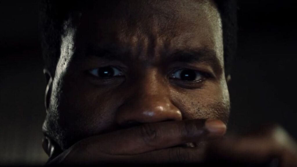 closeup of black man with one hand over his mouth