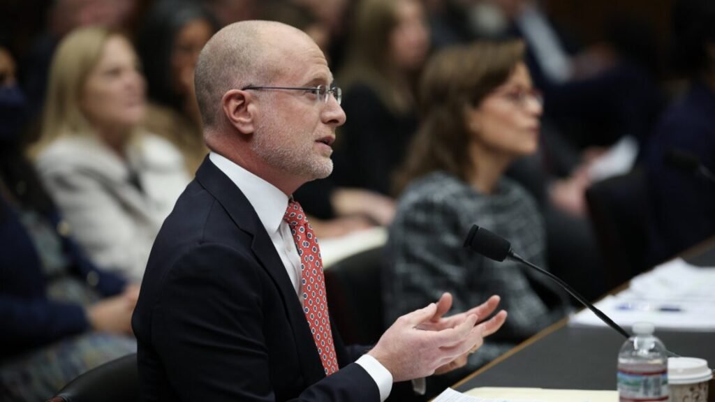 FCC Chairman Brendan Carr speaks into a microphone at a Congressional hearing. FCC Commissioner Anna Gomez sits next to Carr.