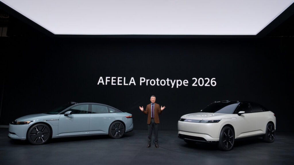 A man stands between two cars on stage