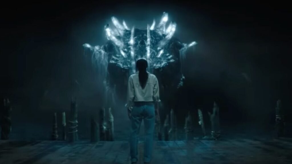 young woman in a dark cave standing with back to camera facing a gigantic monster glowing blue