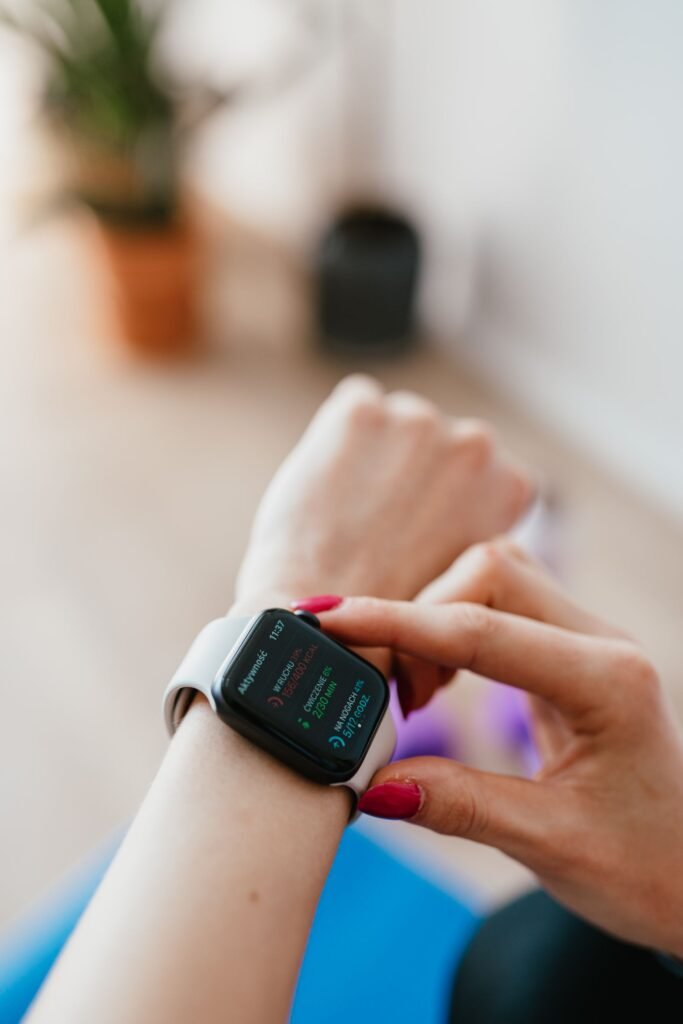 What Should My Move Goal Be on Apple Watch? Woman checking fitness data on a smartwatch while sitting on a yoga mat