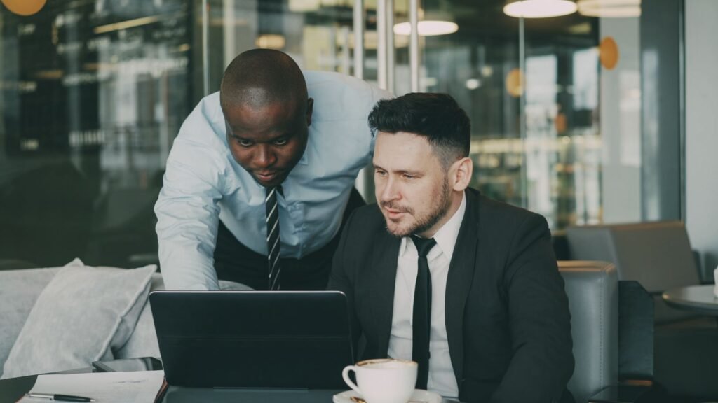 AI’s Biggest Productivity Gains Are Still Ahead, and Small Businesses May Get There First Two business professionals collaborating on a laptop, discussing AI-driven productivity tools in a modern office