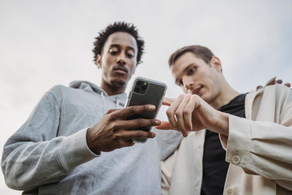 Two friends browsing a smartphone together outdoors