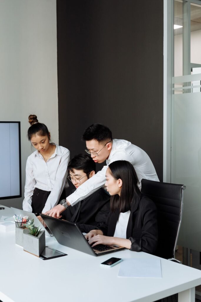How to Use Microsoft Teams: A Beginner’s Guide Business people looking at a laptop together in a team meeting