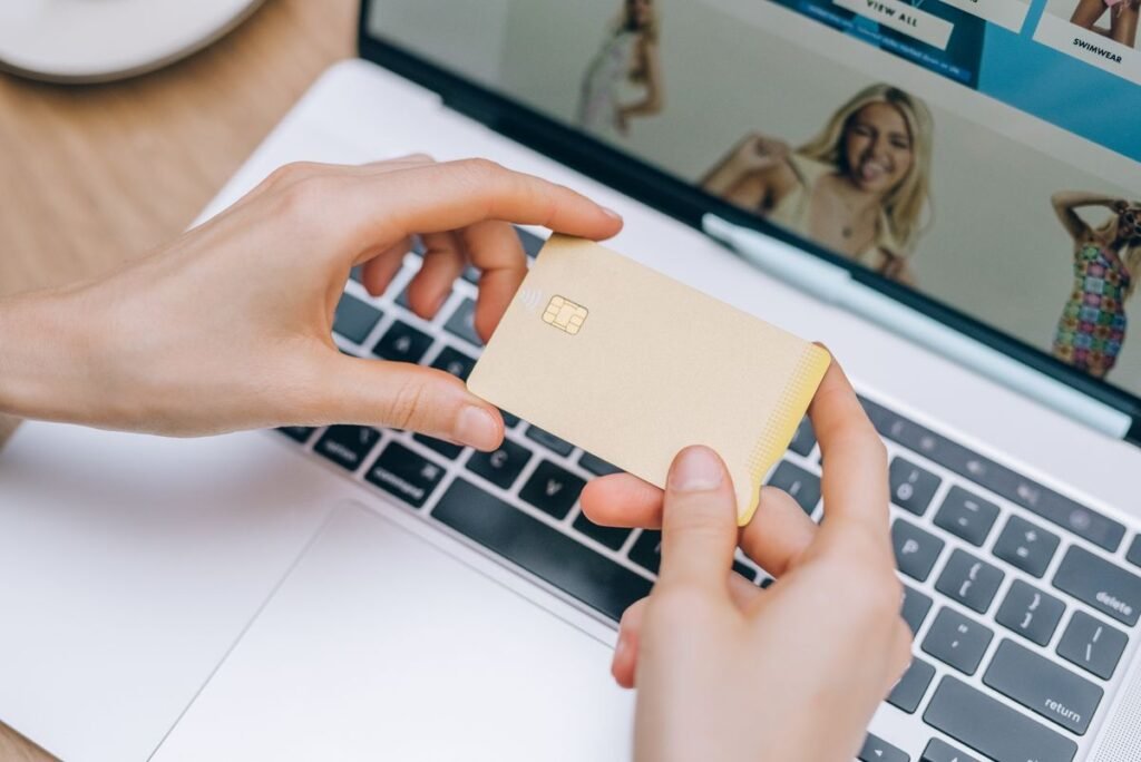 How to Shop Online Safely: A Beginner’s Guide Person holding a credit card while shopping online on a laptop