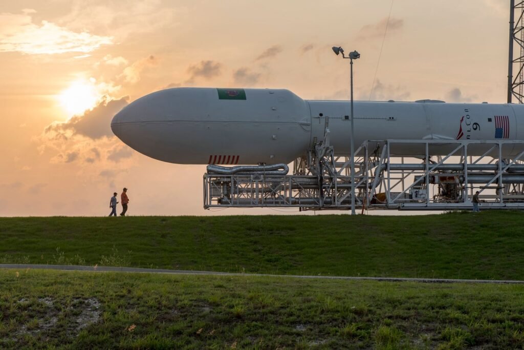 There Is a Sealed Blast Bunker 40 Feet Under SpaceX’s Launchpad, and the Only Way In Was a Slide A launch vehicle standing on a pad at Kennedy Space Center with ground crew nearby at sunset
