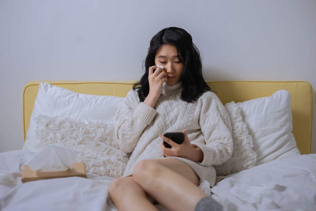 Woman sitting on a bed looking at a smartphone