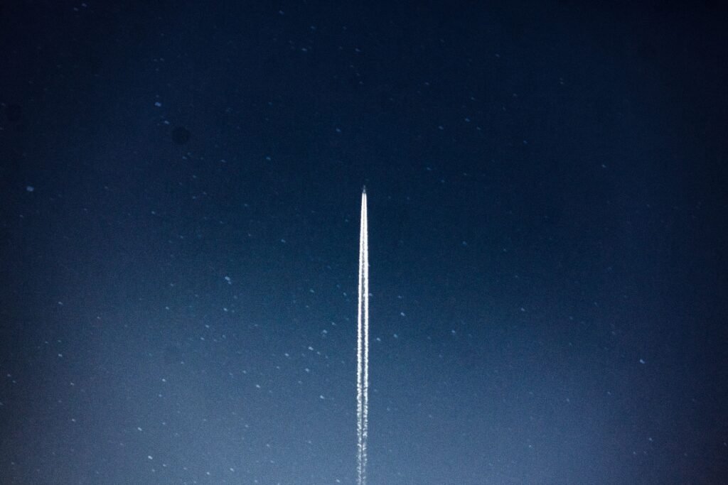 A rocket lifting off against a dark sky, trailing exhaust and light