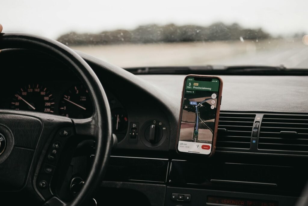 Smartphone mounted on a car dashboard showing a navigation map while driving