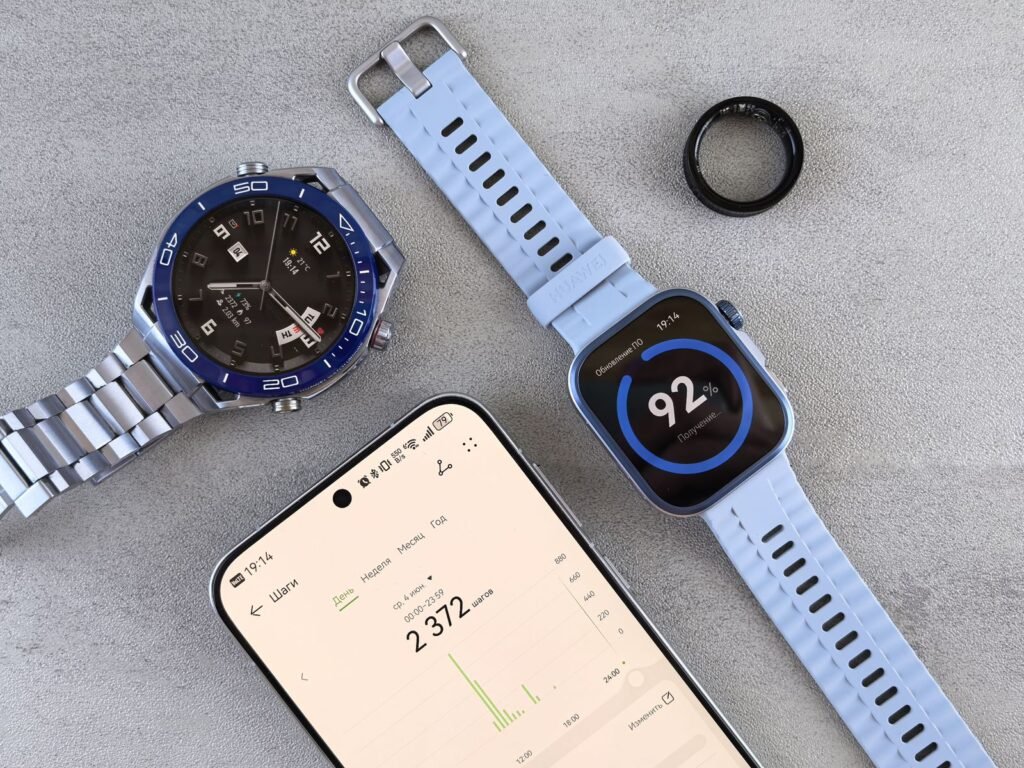 A smartwatch, a smart ring tracker and a phone showing fitness data on a gray surface