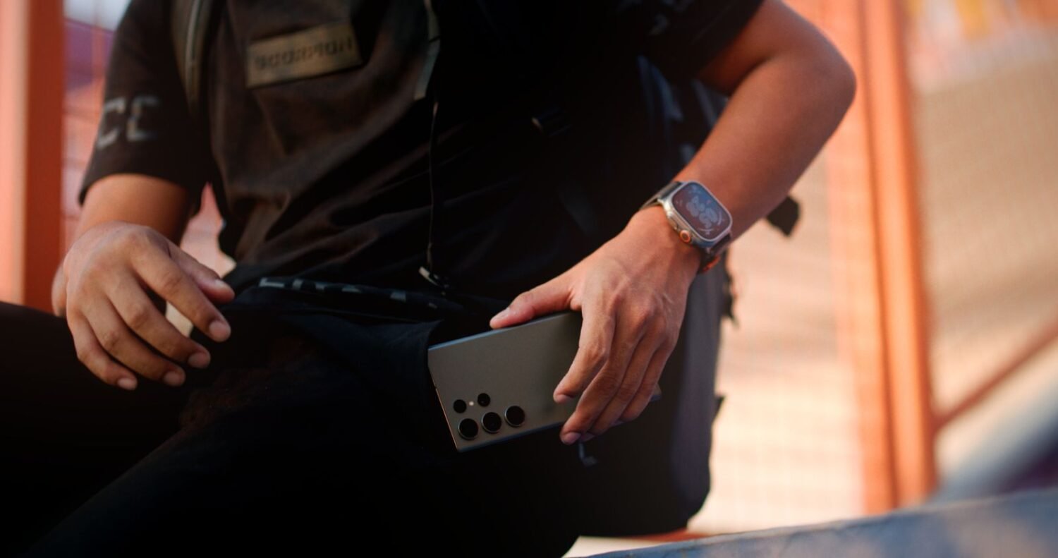 Man checking his smartwatch alongside his Android phone outdoors