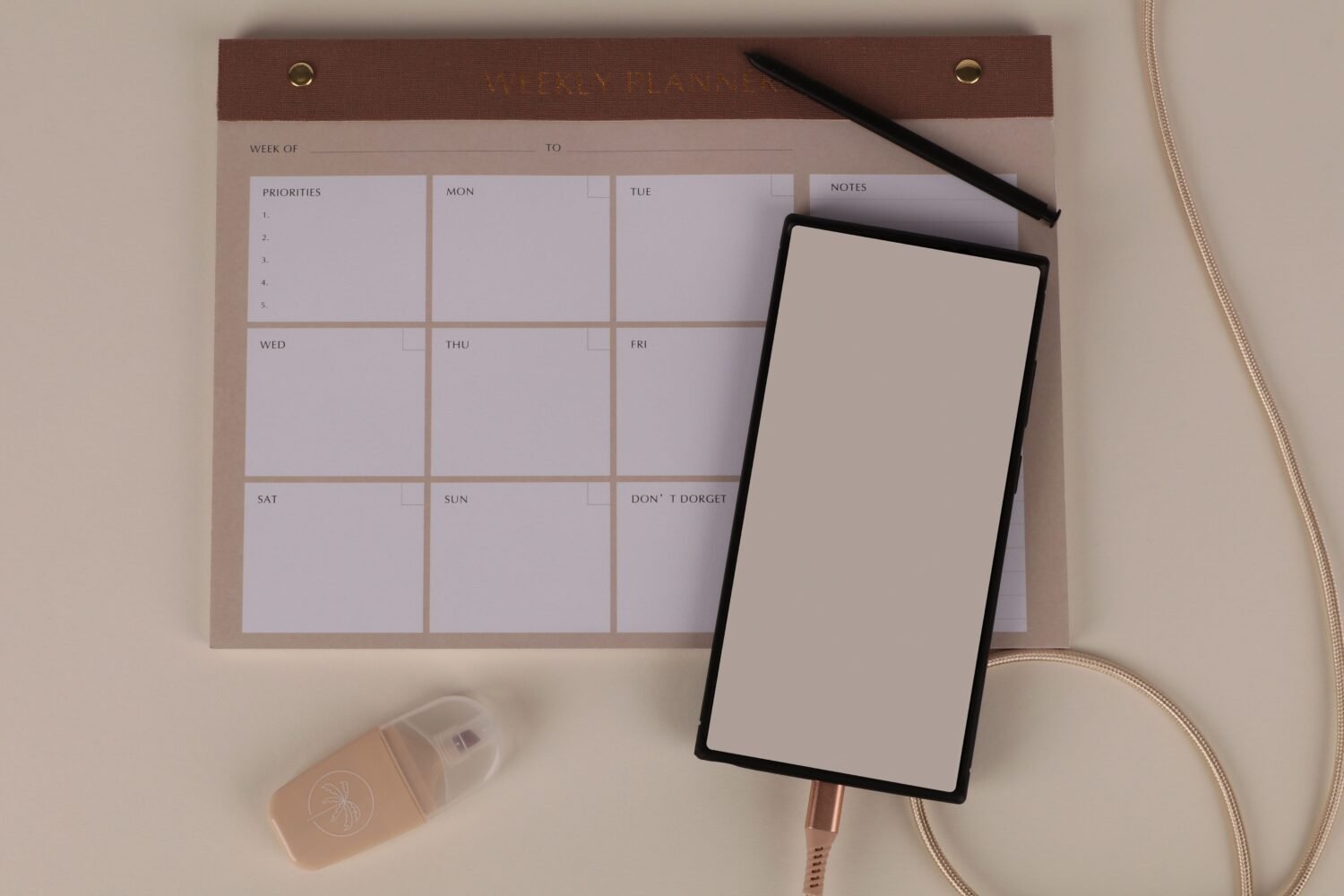 A flat lay desk setup with a weekly planner, a smartphone and stationery
