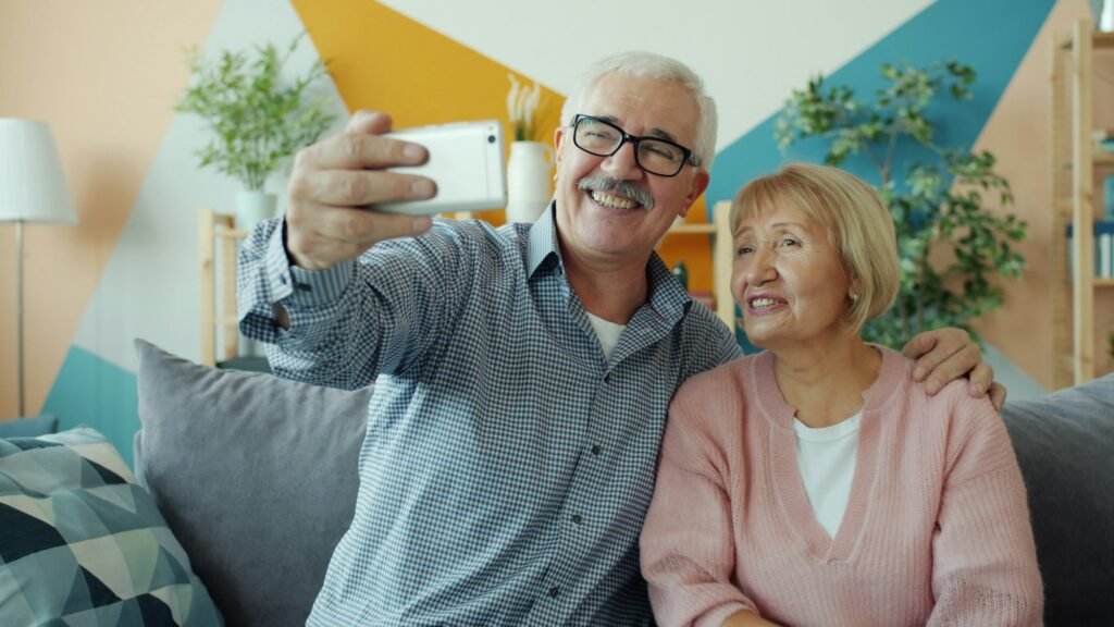 Easy-to-Use Smartwatches for Seniors: The Simplest Picks in 2026 Elderly couple smiling while looking at a smartphone screen together, representing seniors comfortable with simple technology