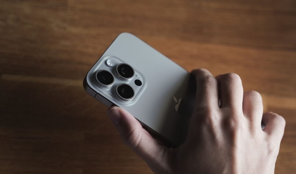 A person holding a modern iPhone Pro in one hand, illustrating an iOS software update decision