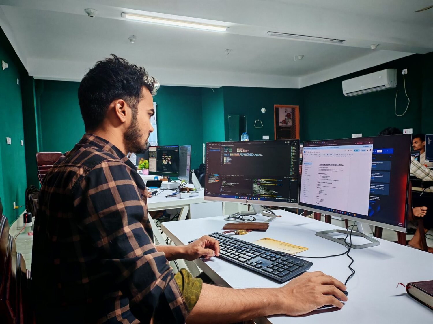Game developer working at a desk with multiple monitors showing code and design tools