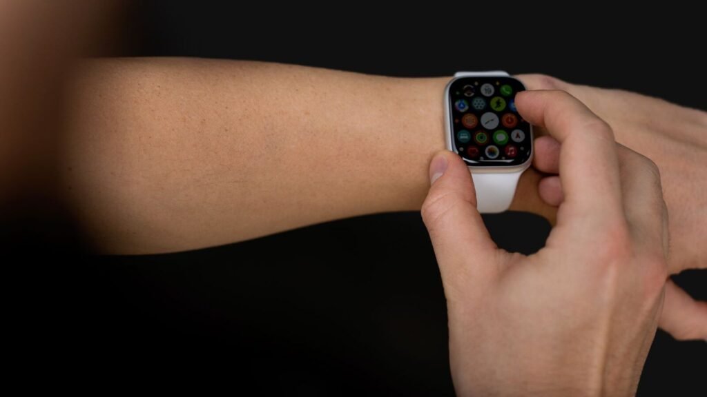 Hand tapping a smartwatch screen against a black background