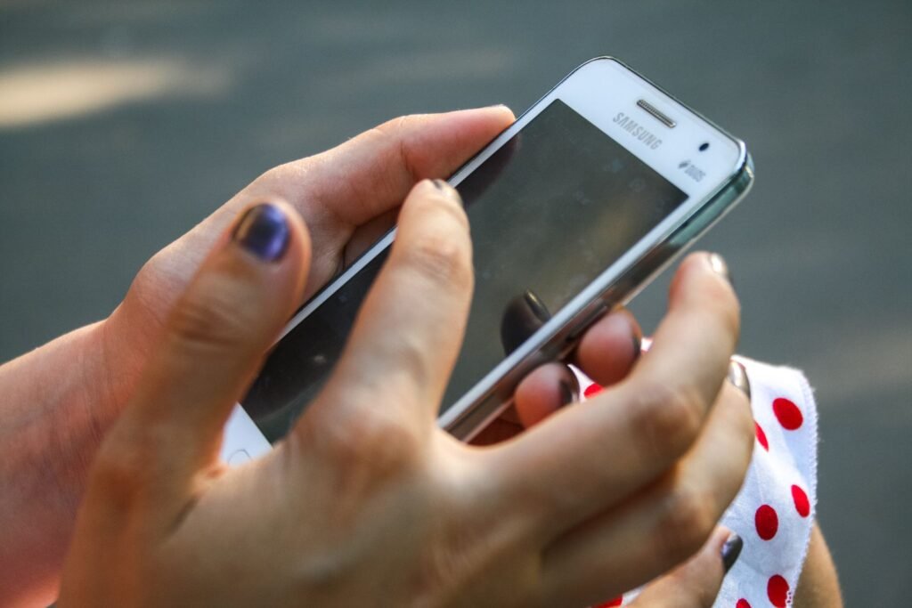 Hand holding a white Samsung Android smartphone for the app pinning feature