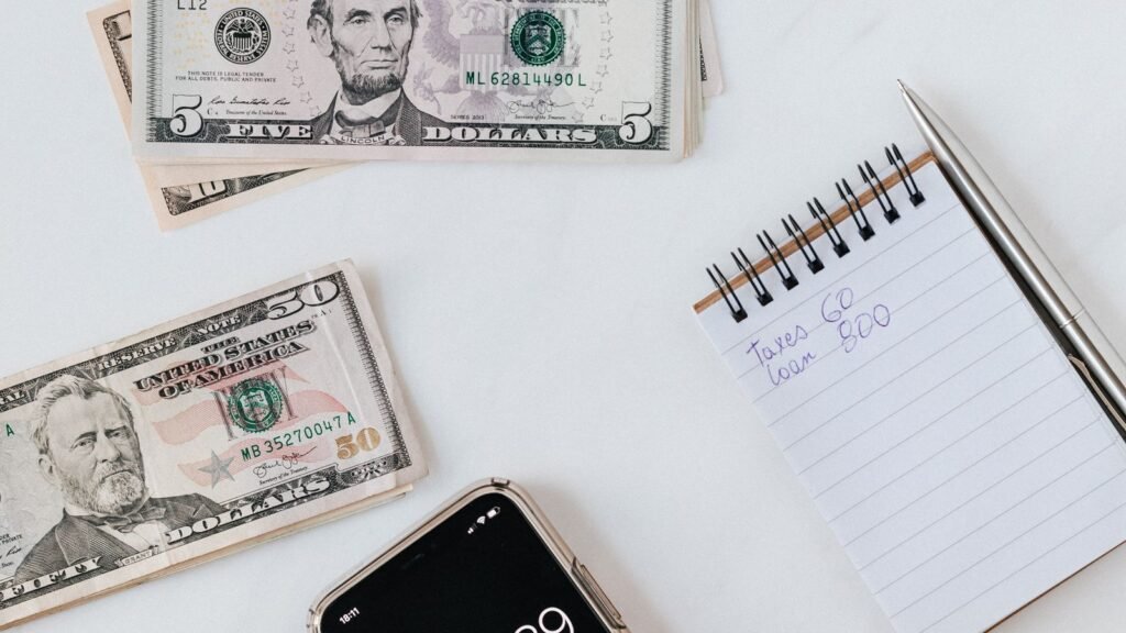 Apple Is Paying $250 Million Over Siri. Seven iPhones Qualify, and You Need the Serial Number. Hands using a smartphone calculator next to US dollar banknotes on a table