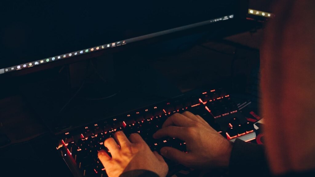 Hands typing on a keyboard in a dark room