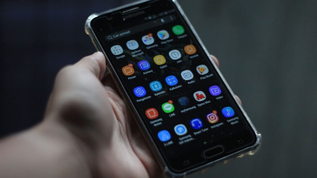 Person holding a smartphone with apps on screen