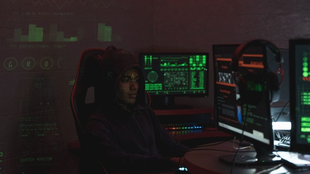 How to Recover a Hacked Facebook Account (2026) Man in a hoodie working at multiple monitors on account security