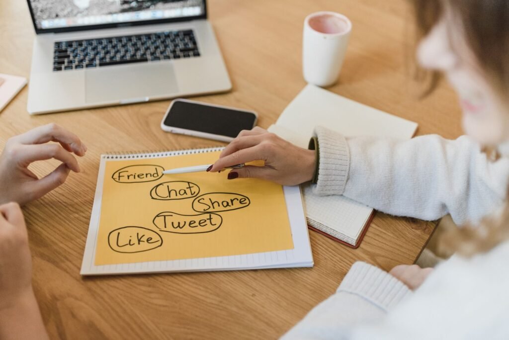 Two women planning a social media strategy for a small business with a laptop and smartphone