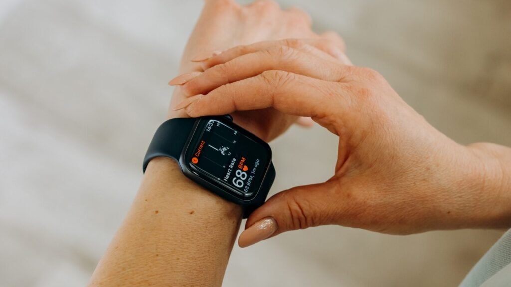 Woman looking at health and heart rate data on her black smartwatch indoors