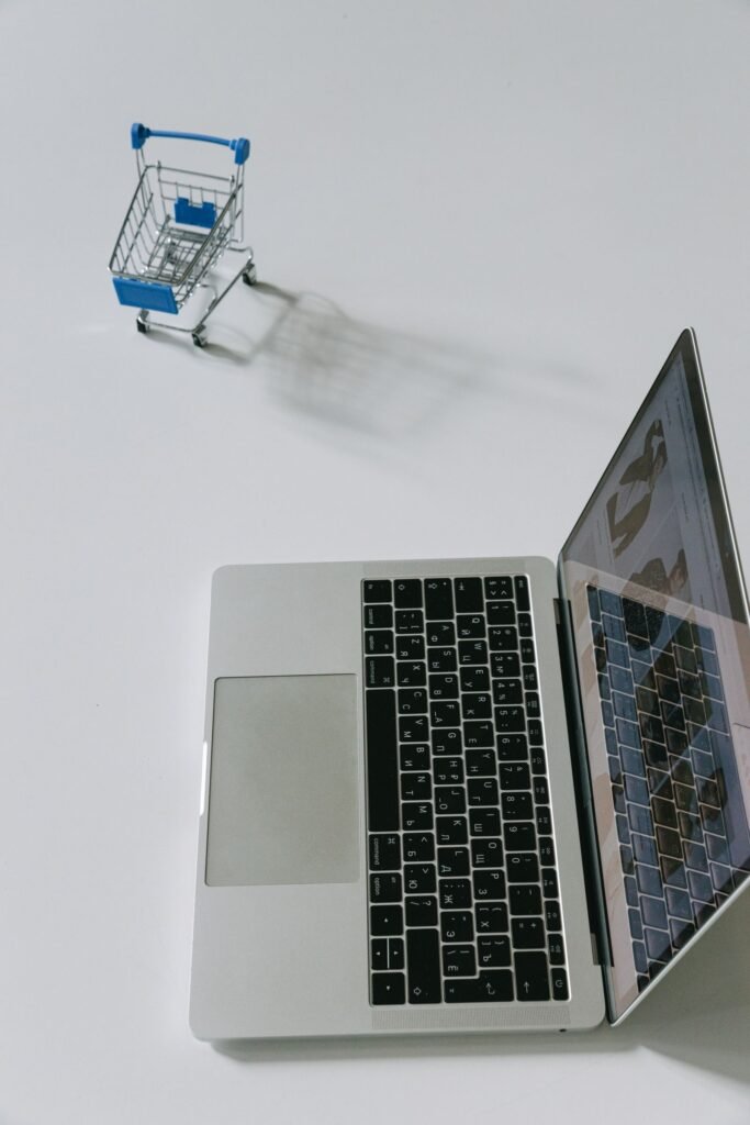Laptop beside a miniature shopping cart for running an OpenCart store on HostGator