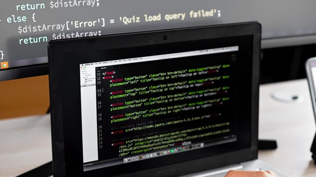 Person coding at a desk with a laptop and an external monitor
