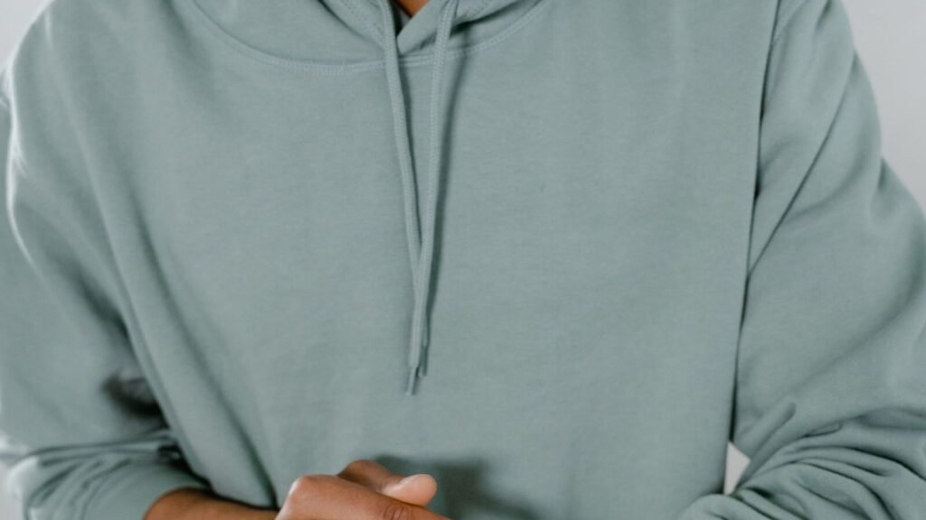 Man in a green hoodie checking the time on a smartwatch