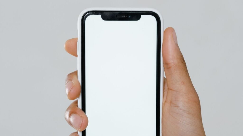 Hand holding a modern smartphone with a blank screen, illustrating Apple's iPhone lineup and the foldable iPhone Duo