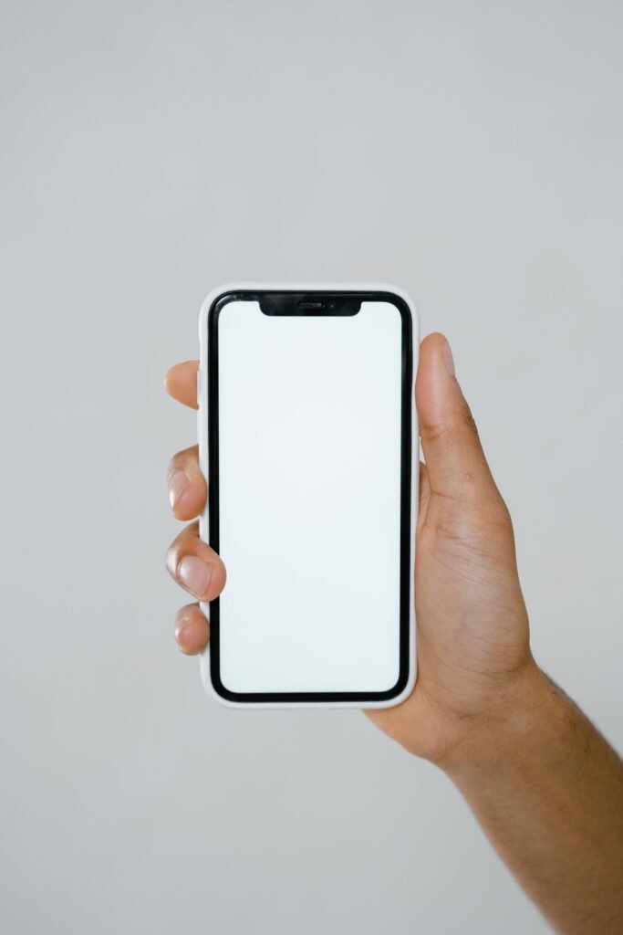 Hand holding a modern smartphone with a blank screen, illustrating Apple's iPhone lineup and the foldable iPhone Duo