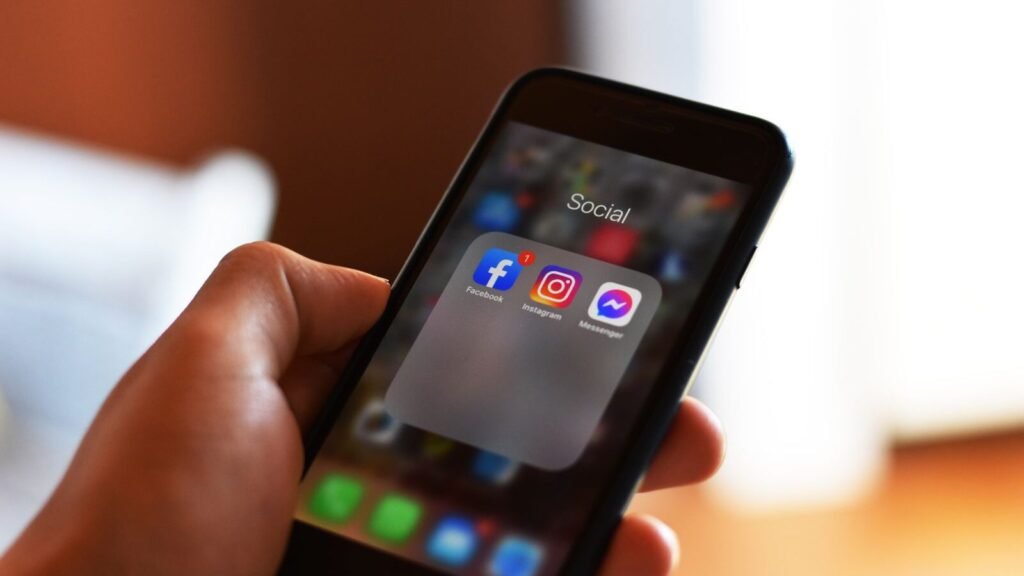 Hand holding a phone showing Facebook and Instagram