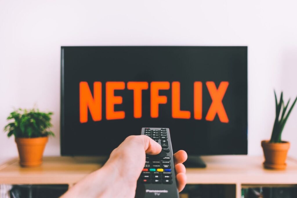 Person holding a TV remote control pointed at a screen