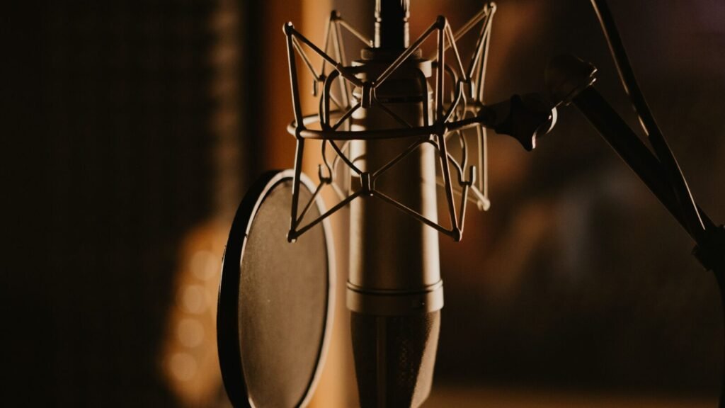 Close-up of a studio microphone behind a pop filter in a dimly lit recording room