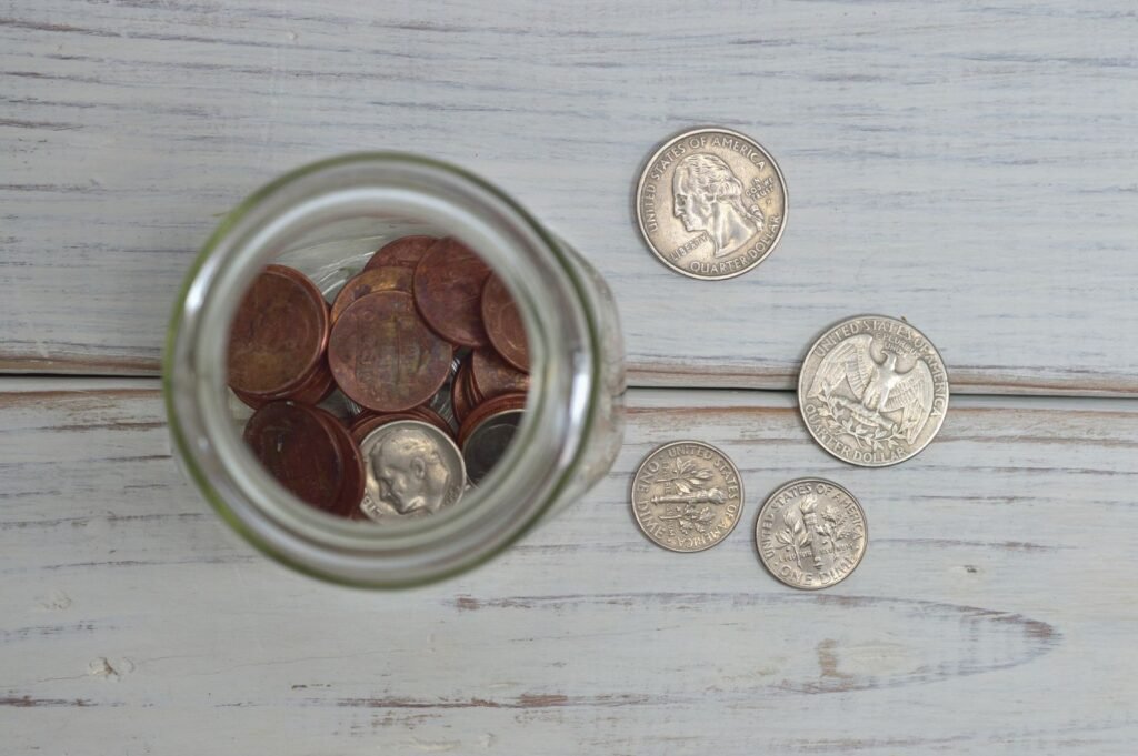 A glass jar filled with coins sitting on a wooden surface, representing retirement savings