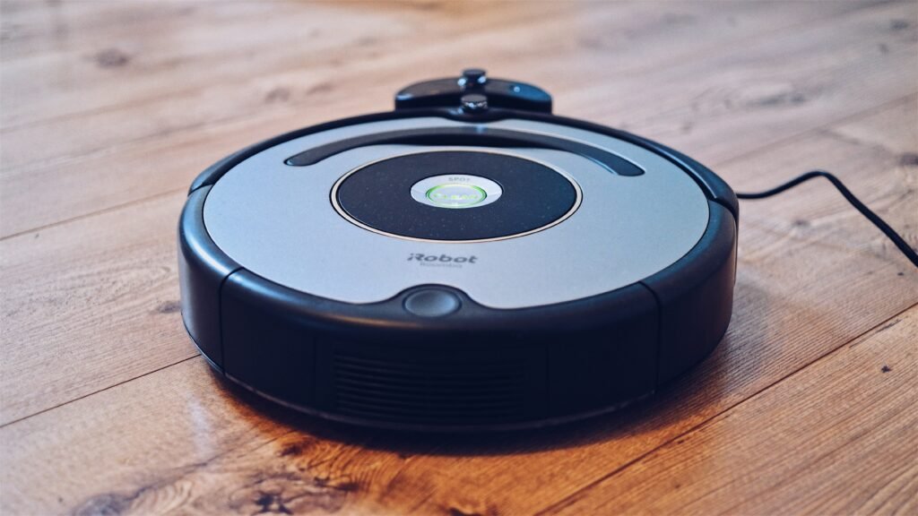 A round robot vacuum cleaner moving across a hardwood floor, illustrating smart home camera and privacy concerns