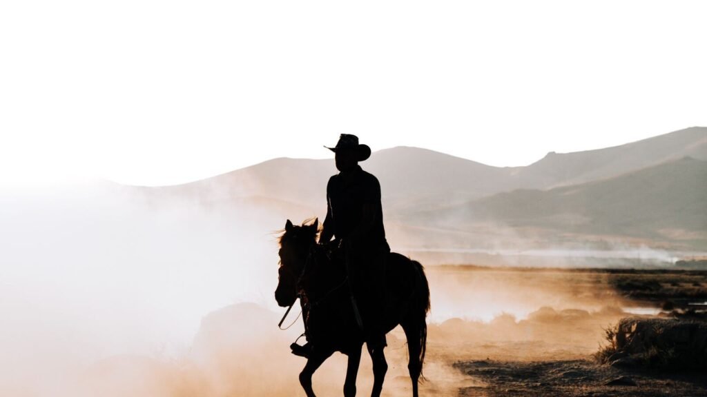 What Happens to Sadie in RDR2? Her Full Story and Ending Explained Lone rider silhouetted against dawn light on a dusty plain, evoking Sadie Adler's bounty hunting years in Red Dead Redemption 2