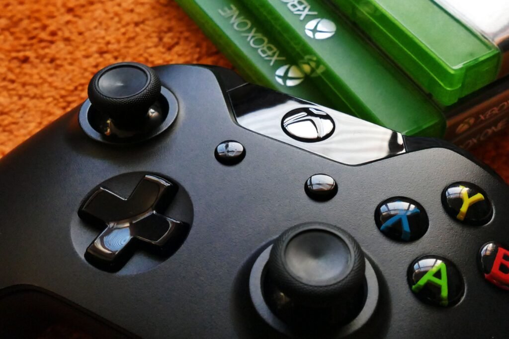 Xbox Disc to Digital Is Now Live for Everyone, but the License Follows the Disc Xbox controller resting next to three Xbox One physical game cases