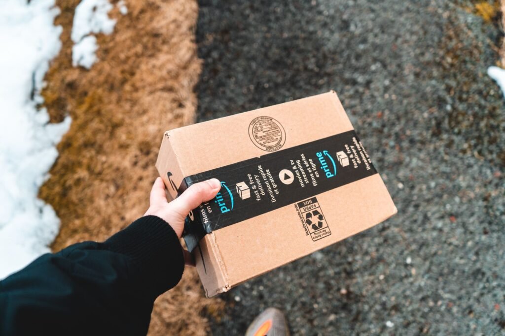 Amazon Has Been Writing Down Guesses About Your Body. The Page Is Two Taps Away. A person carrying a cardboard Amazon package, the purchase history that feeds Amazon's About You shopping profile