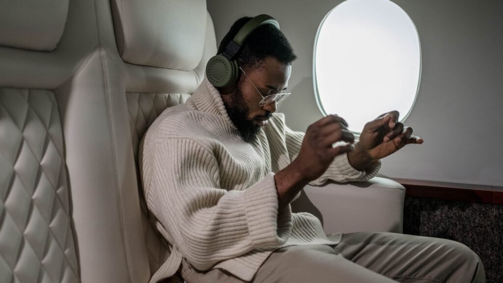 Man with headphones in an airplane seat next to the window, listening to music offline