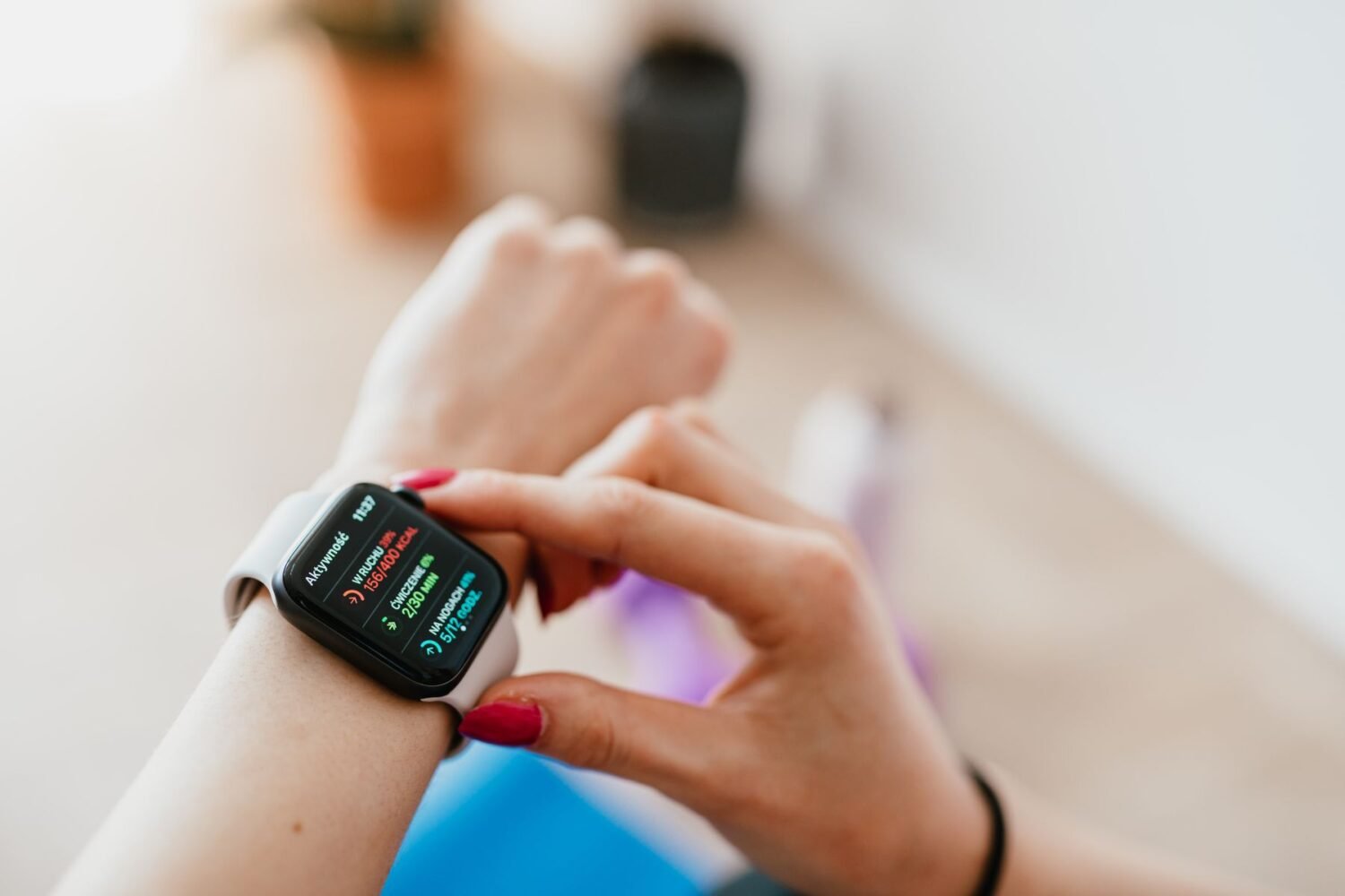 Woman checking her smartwatch while sitting on a mat at home