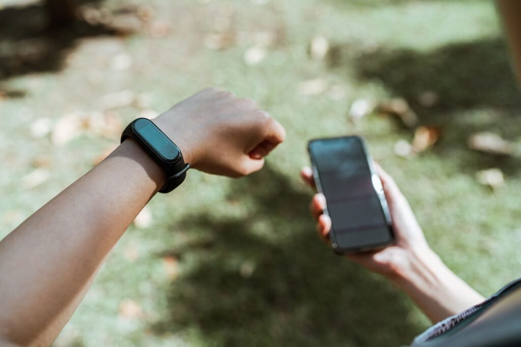 Person showing a smartwatch on their wrist while holding a smartphone outdoors