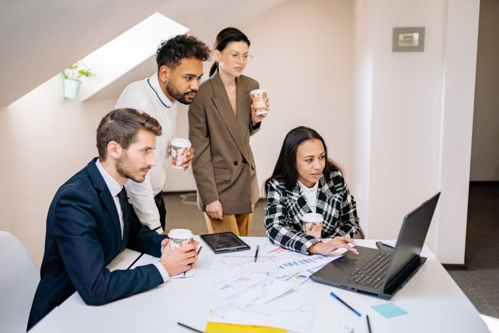 Colleagues working together at a laptop in a modern office, illustrating AI agents joining the workplace