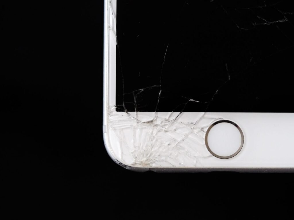 Close-up of cracked glass on the corner of an iPhone screen against a black background