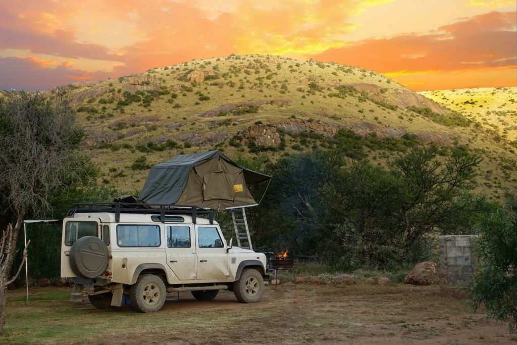 White Land Rover Defender with a rooftop tent parked at sunset in the South African Karoo