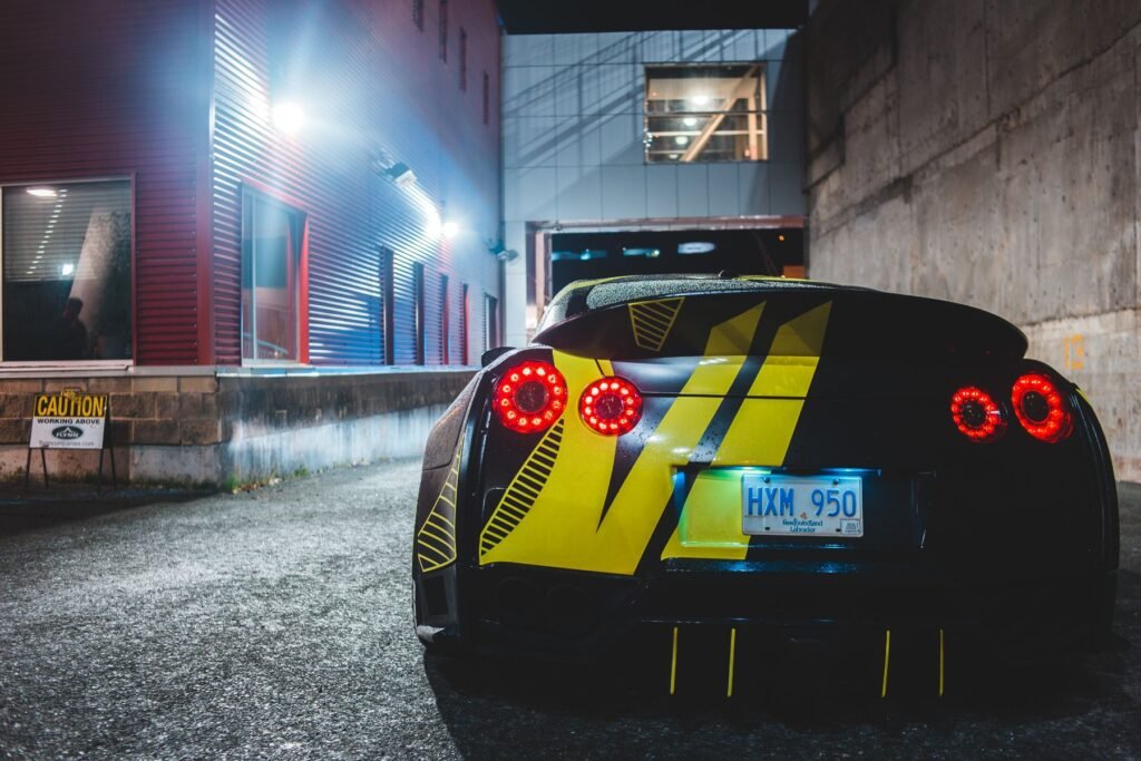 Low black sports car on a city street at night with lights glowing