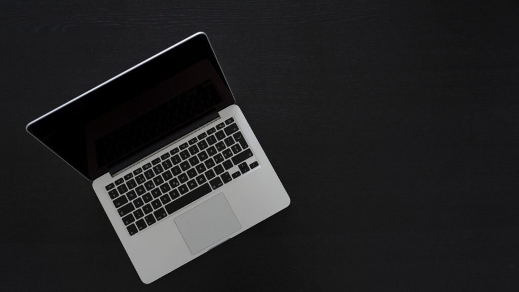 Apple’s First Touchscreen MacBook Pro Starts at $2,899. Fans Are Cheering Louder for the Glowing Logo. Open MacBook Pro laptop on a dark desk seen from above