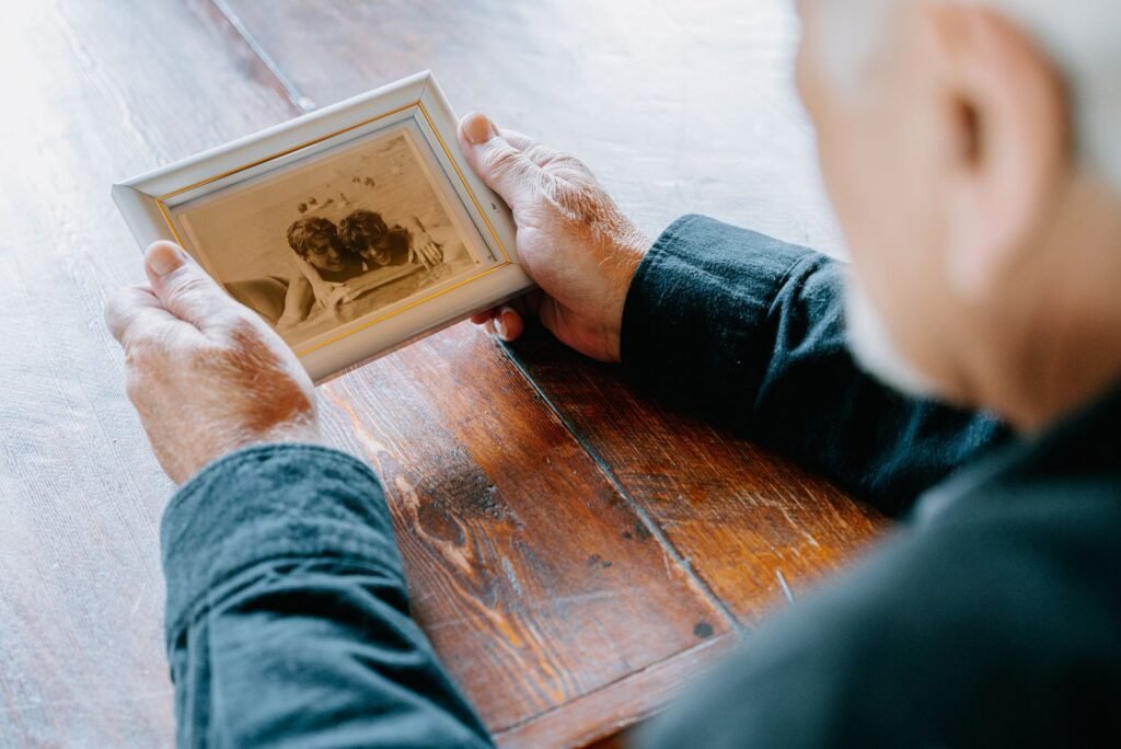 An older man holding an old printed photograph